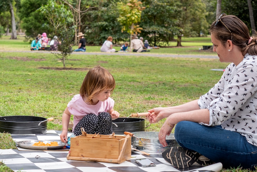 A 2-year-old child plays in a park with her mother.