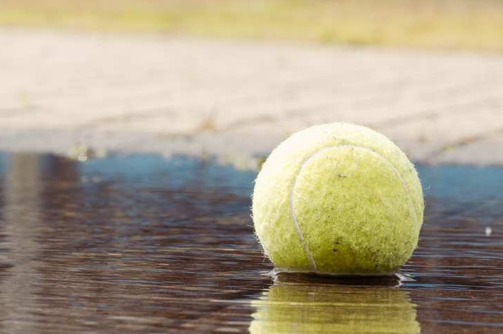 A tennis ball sits in a puddle.