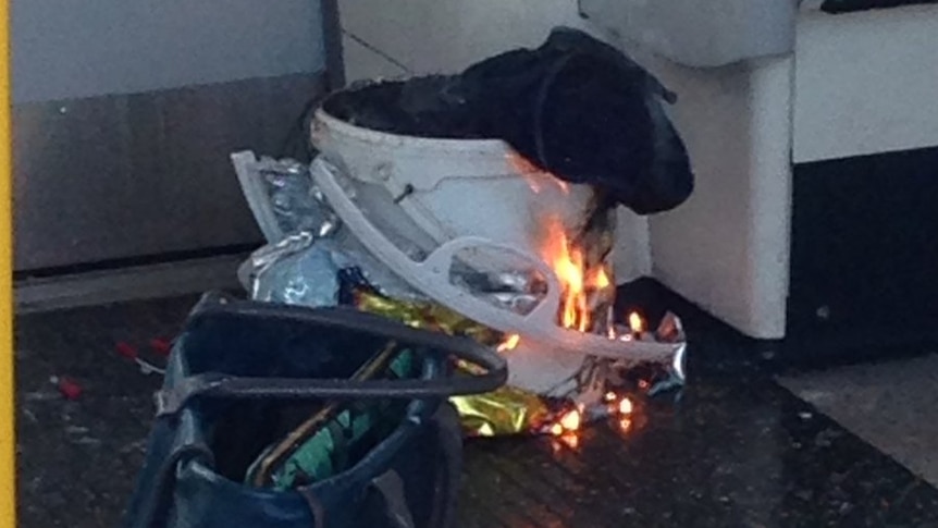 A white container inside a plastic bag burns on a London Underground train.