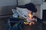 A white container inside a plastic bag burns on a London Underground train.