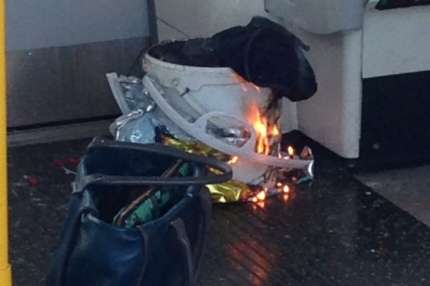 A white container inside a plastic bag burns on a London Underground train.