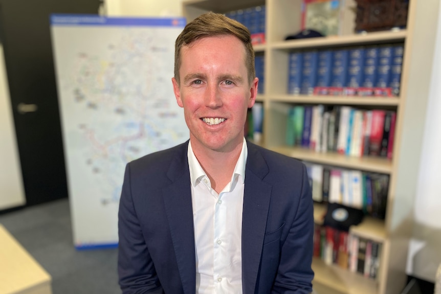 A man in a navy blue suit smiles.