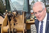 Scott Morrison poses in front of a digger while a camera operator positions a boom mic above him and a man in a suit walks past.
