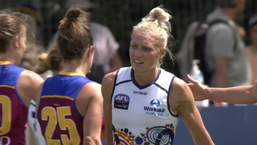 Erin Phillips smiles and walks past two girls heading in the other direction
