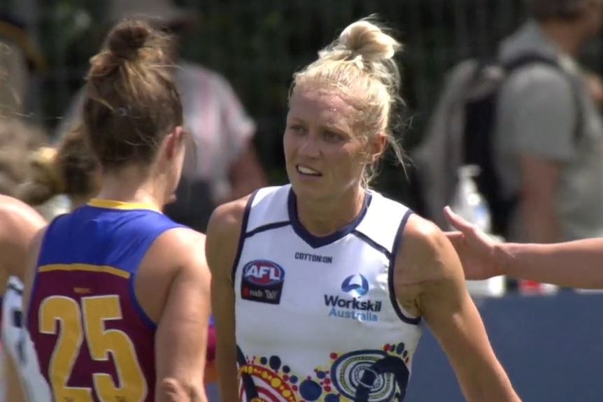 Erin Phillips smiles and walks past two girls heading in the other direction
