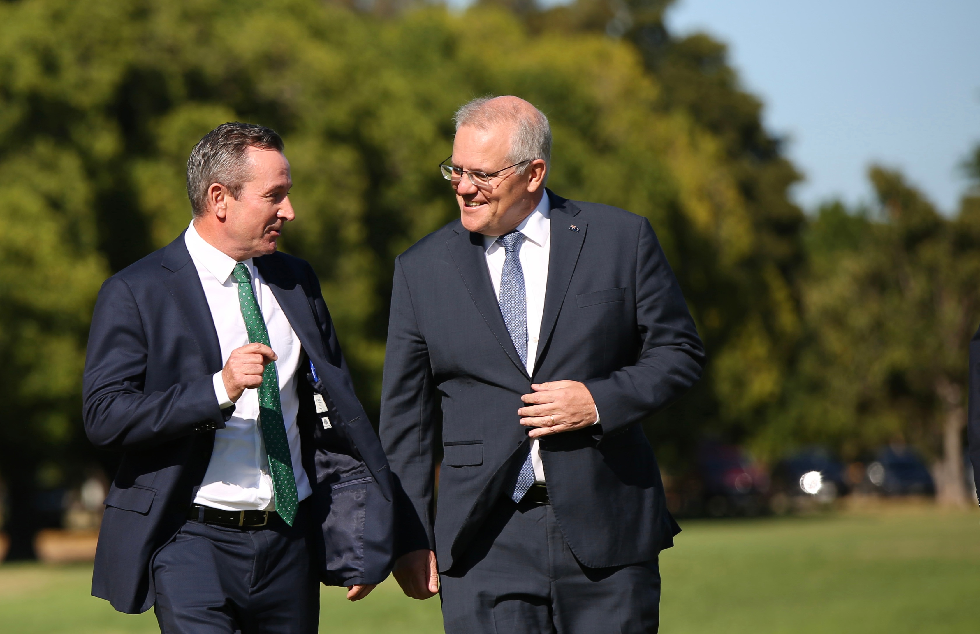 Two men share a joke while walking in a park.
