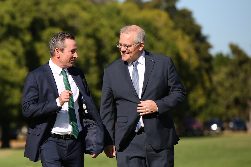 Two men share a joke while walking in a park.