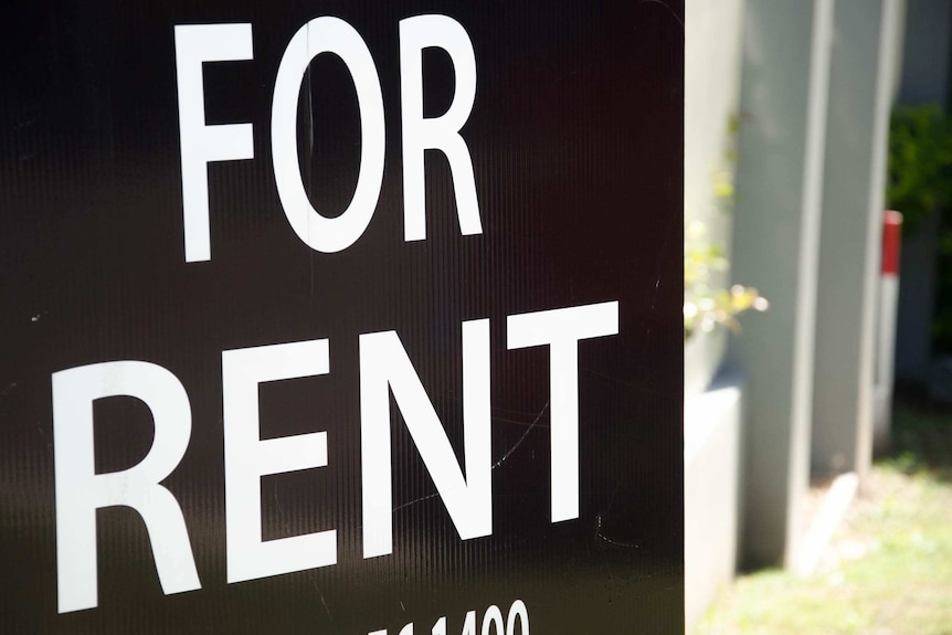 A black and white for rent sign outside a house.