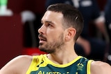 An Australian male basketballer sits on the boards during their Tokyo Olympics game against USA.