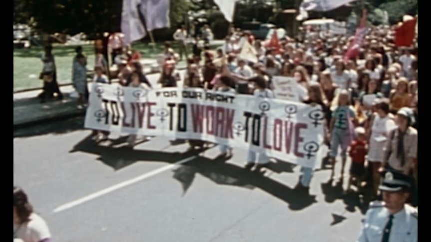 Street demonstration, people hold banner with text "For our right to live, to work, to love"