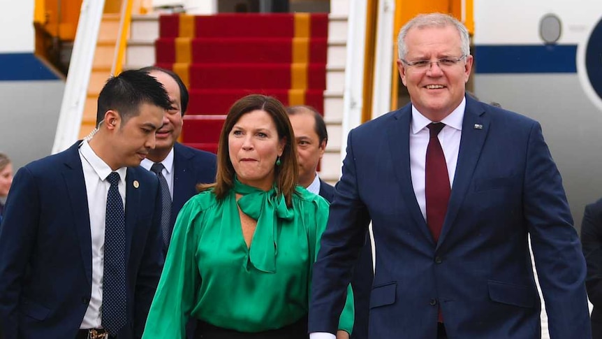 Australian Prime Minister Scott Morrison (centre) and his wife Jenny step off a plane.