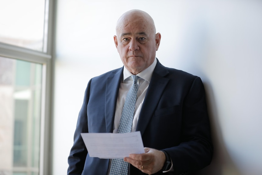 A man in a suit and tie holding a piece of paper in an inner city office