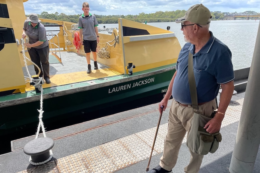 Man with a walking stick stares back at Sydney ferry.