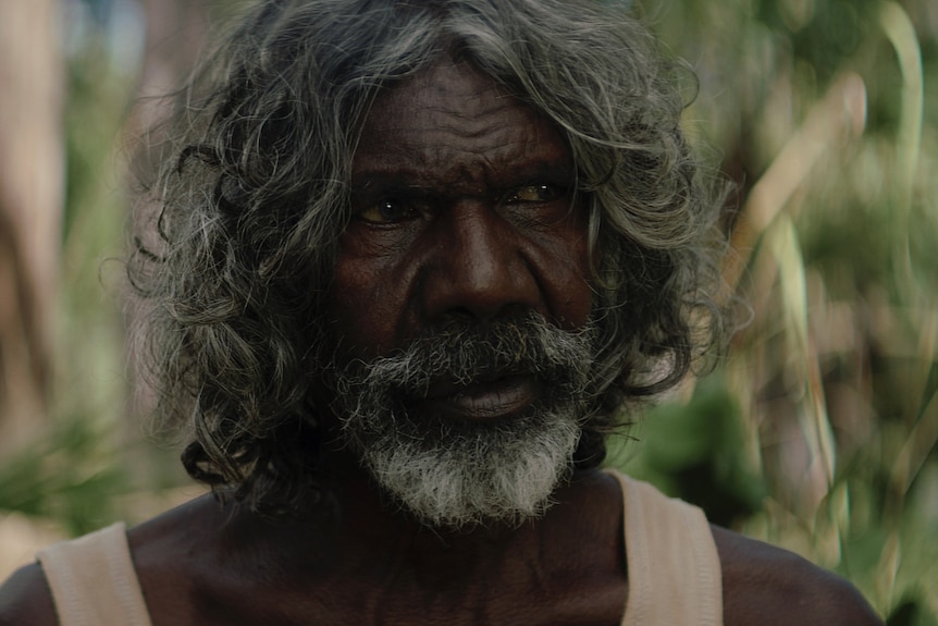 Actor David Gulpilil, an older Yolngu man in a white singlet out in the forest on 2013 film Charlie's Country