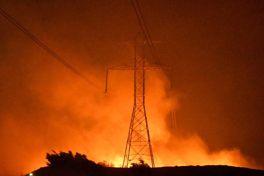 A fire rages around a power line