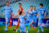 An A-League striker looks at his excited teammates who are congratulating him on his goal.
