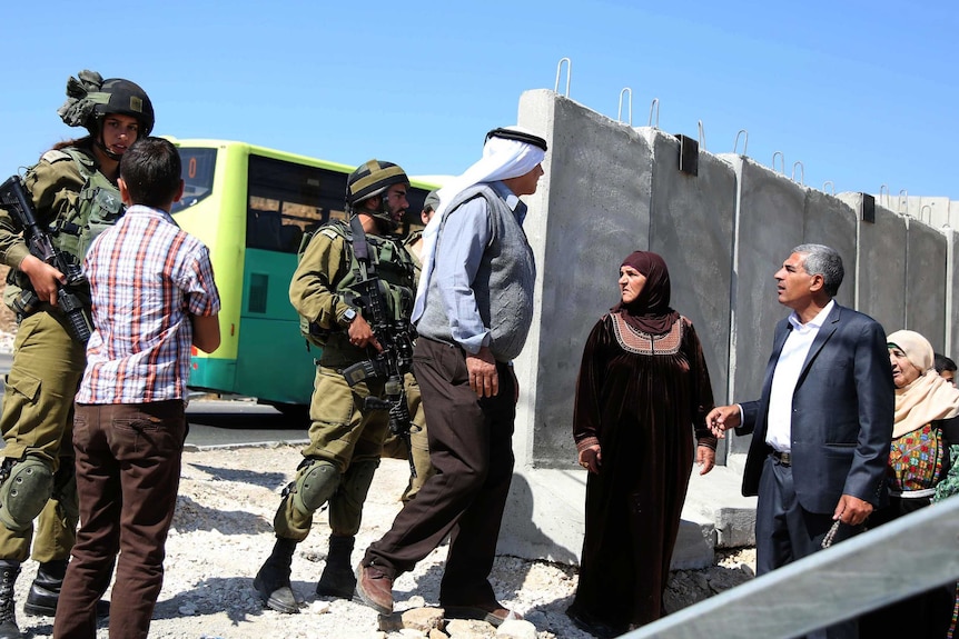 Israeli security guards talk with Palestinians as security measures are increased in the Hizma district of Jerusalem.