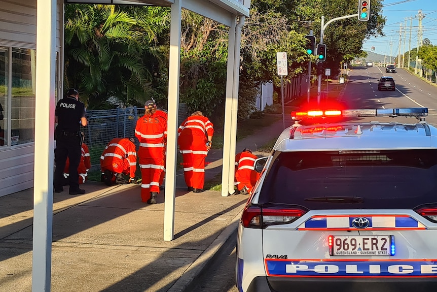 SES volunteers down on the ground next to a police car. 