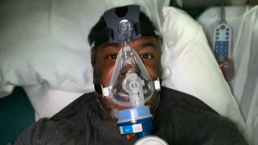 Selfie of a man laying in hospital bed with a ventilator on