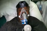 Selfie of a man laying in hospital bed with a ventilator on