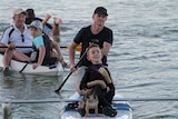 Riley Saban sits on the the front of a paddleboard while his father Clint paddles.