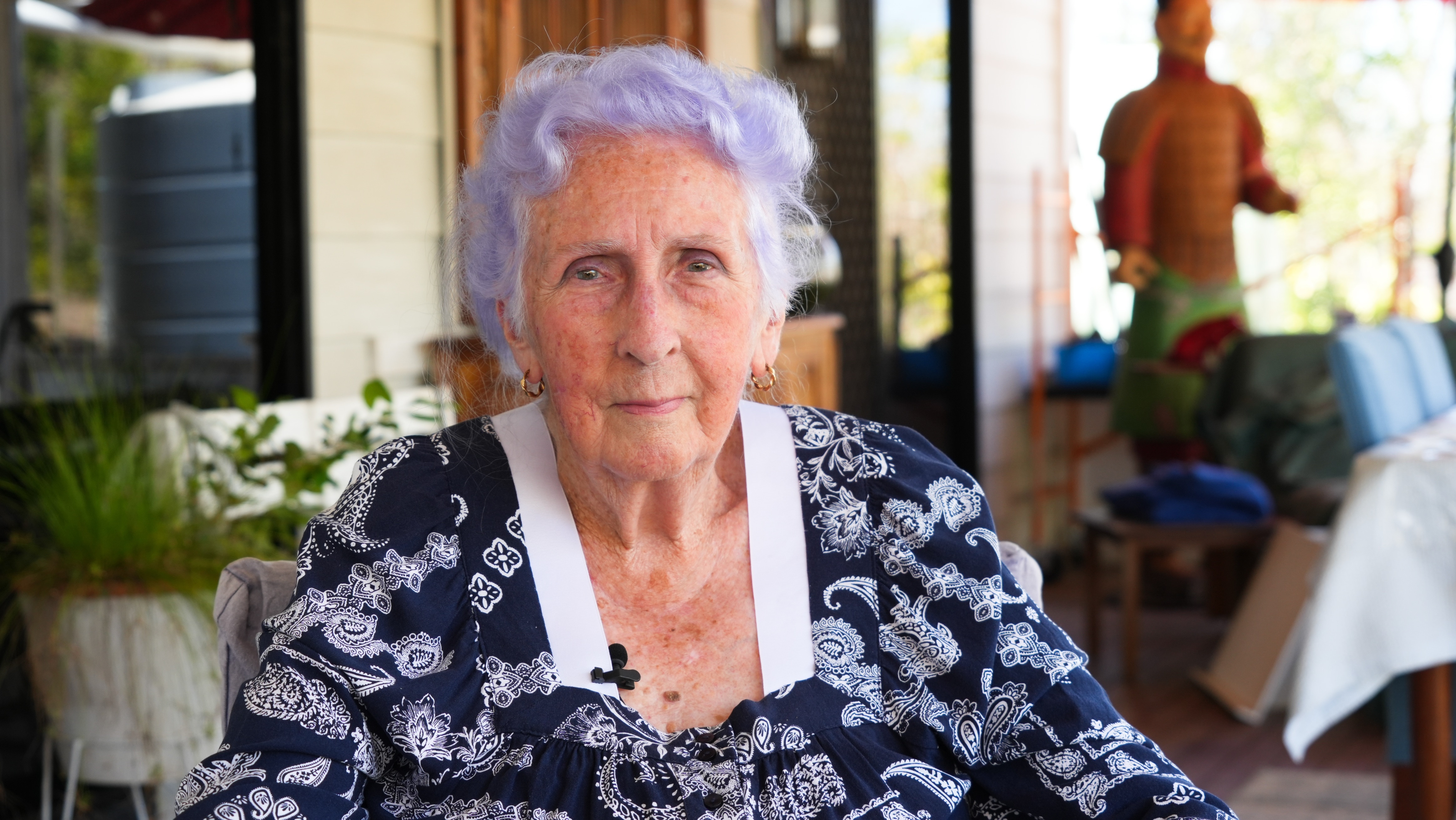 elderly lady with purple hair sitting in seat.