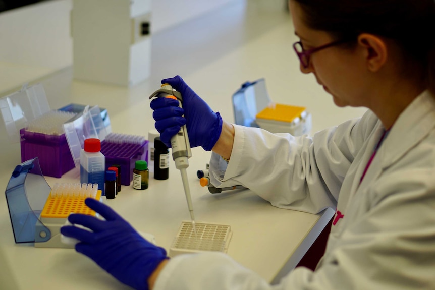 A Linear researcher works on some samples in the lab wearing a white coat and glasses.