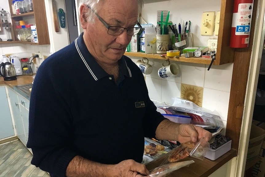 A man looking at packets of dried fruit in his kitchen