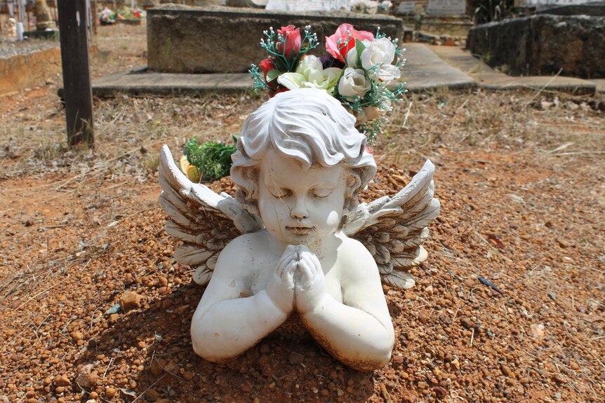 A cherub gravestone with flowers