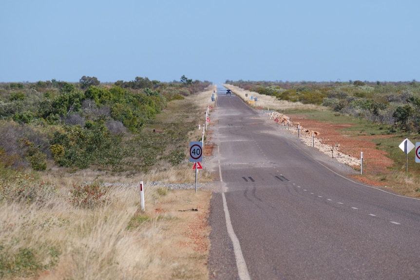 A stretch of the Barkly Highway with warning signs littering the edge of the road and clear dangerous drop offs at the road edge