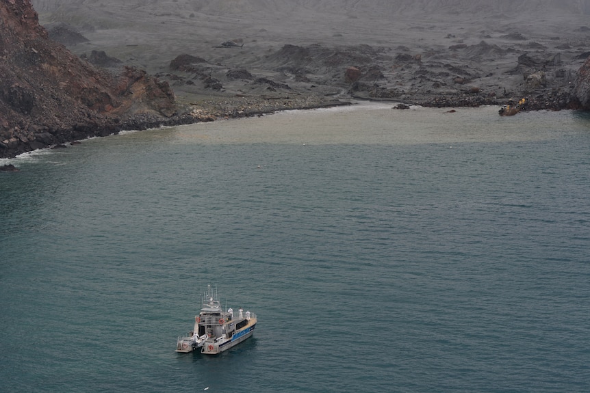 The shore and a boat in the ocean near a barren landscape