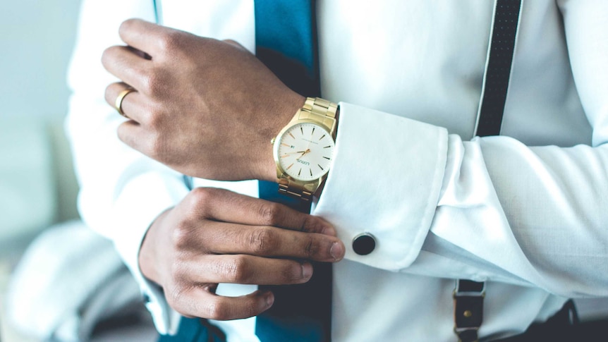 A businessman wearing a crisp white shirt and fancy gold watch