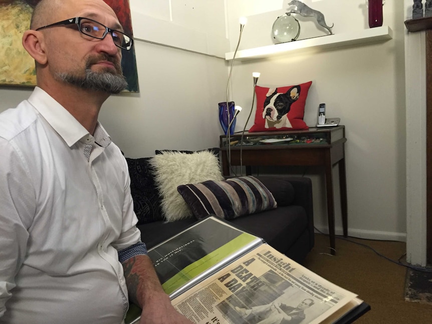 Lloyd Grosse, 51, at his Newtown home, looking at a newspaper article on HIV from 1991