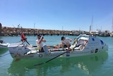Two men sit in a white boat at Geraldton harbour.