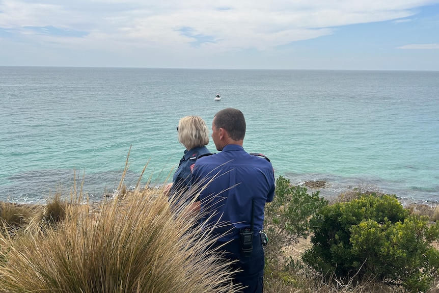Two paramedics stand looking out over the waters of Port Phillip Bay.