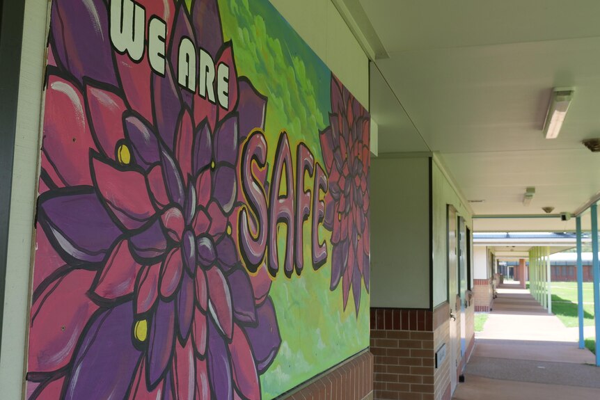 A colorful mural reads "we are safe" in a school corridor. 