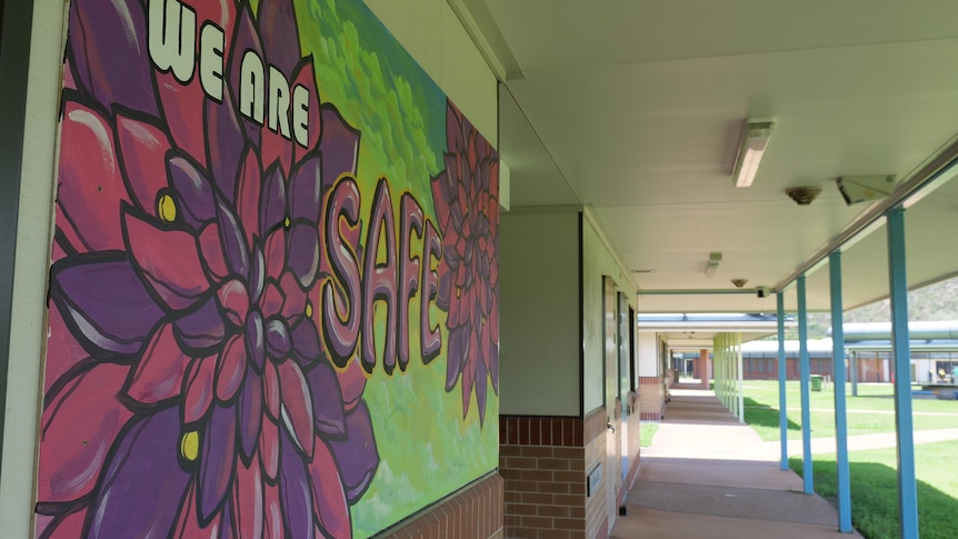 A colorful mural reads "we are safe" in a school corridor. 