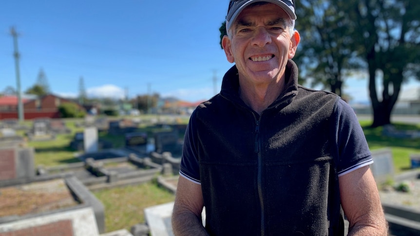 Harvey Jones standing in the middle of a cemetery, smiling. 