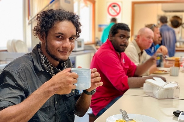 Image of several met eating a meal at a shared table.