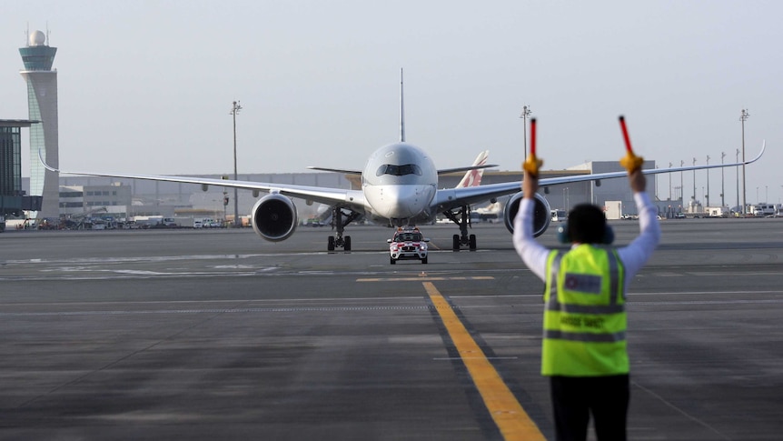 An aircraft marshall signals as an airbus taxis on the runway at Doha Airport in Qatar