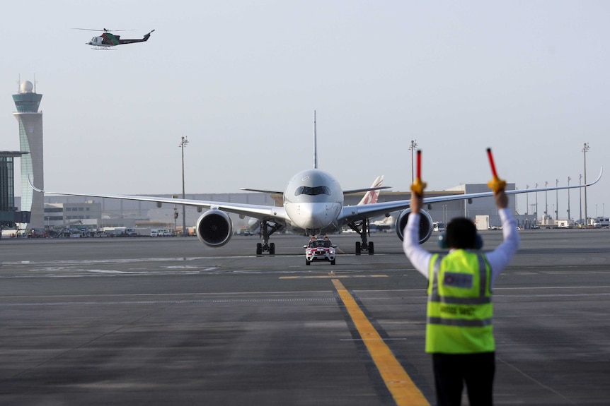 An aircraft marshall signals as an airbus taxis on the runway at Doha Airport in Qatar