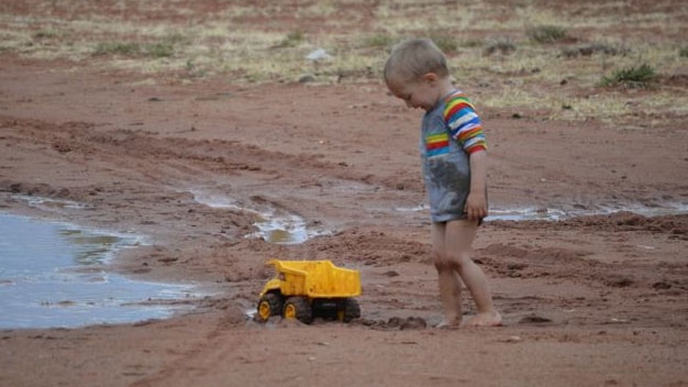 A child plays in the rain near drought-ravaged Windorah, south-west of Longreach in outback Qld on August 15, 2014