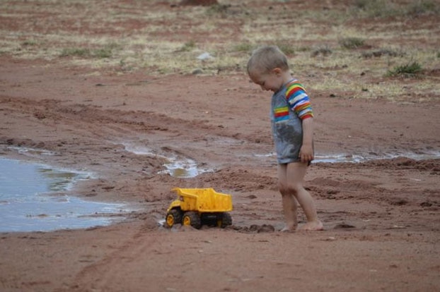 A child plays in the rain near drought-ravaged Windorah, south-west of Longreach in outback Qld on August 15, 2014