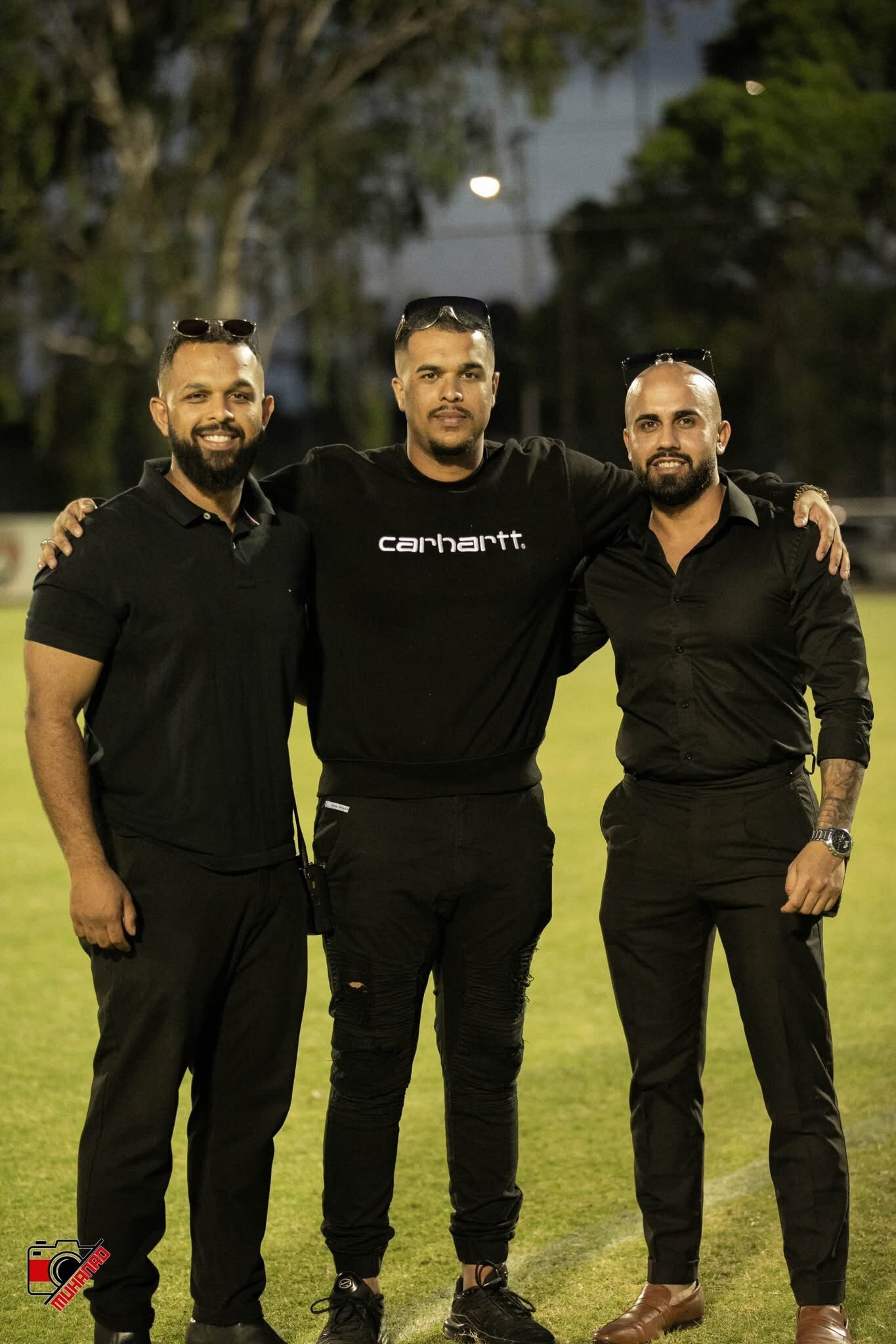 Three men standing with their arms around their backs