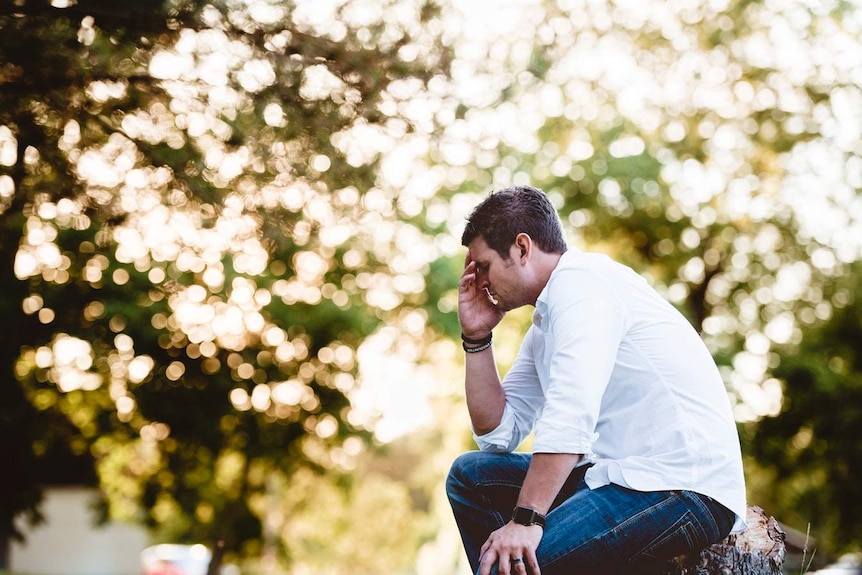 A man holds his head in his hands.