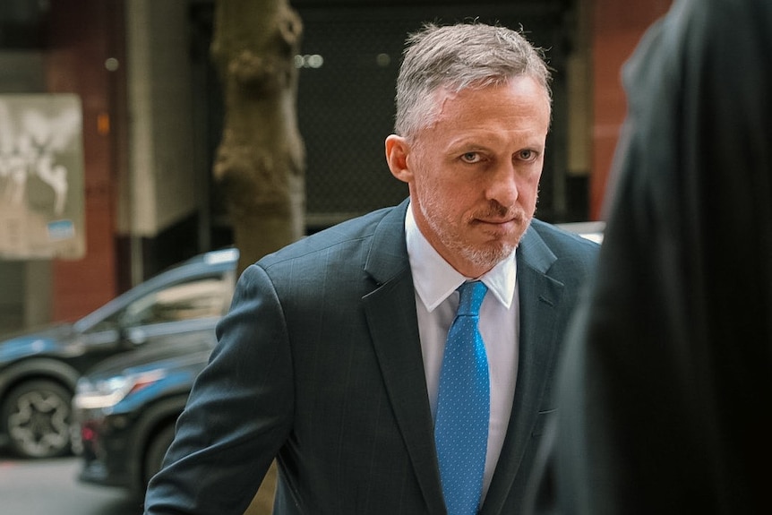 A man wearing a suit peers up as he walks on stairs