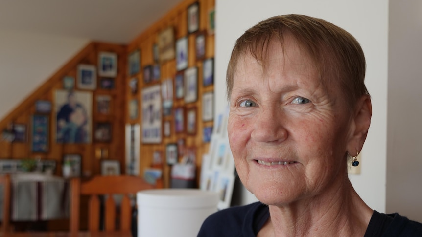 Carol Onley sitting in front of family photos