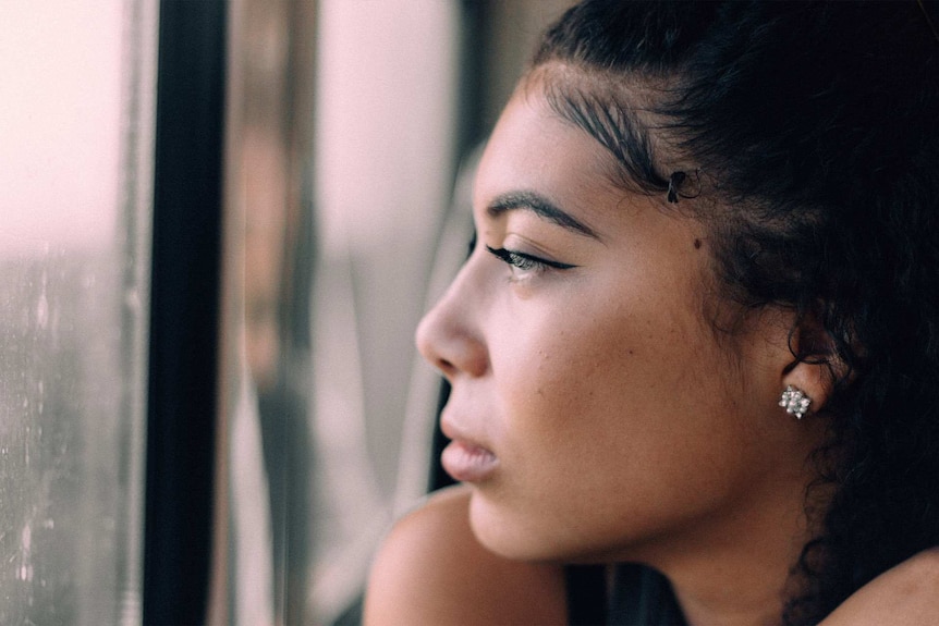 Woman looking pensively out the window for a story about breaking up when the timing isn't right.