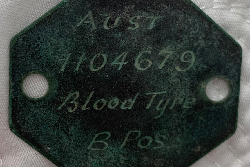 an old identification tag found in a rock pool, it has 'aust' 'b pos' and '1104679' engraved on it