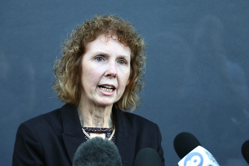 Headshot of a woman in front of microphones.